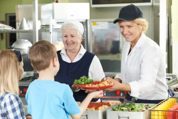 two women serving food to children