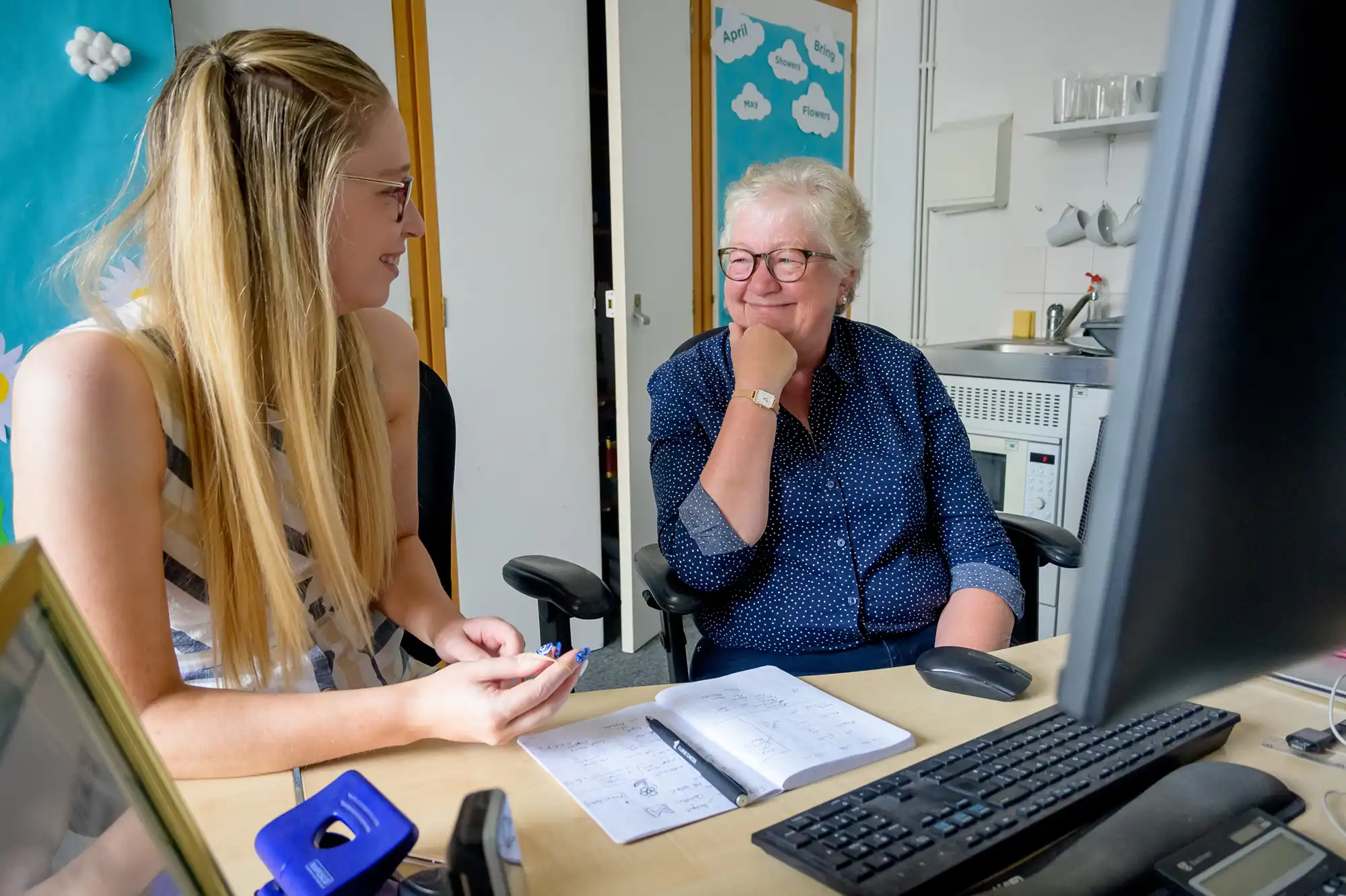 An apprentice sitting at a desk with a mentor